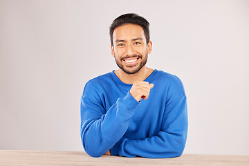 Image showing Smile, table and portrait of a man happy to relax on a desk feeling confident isolated in a studio white background. Resting, calm and young male person looking handsome, friendly and with style