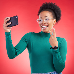 Image showing Happy black woman, peace sign and selfie for photography against a red studio background. African female person or model smile for photograph, memory or social media and online post in happiness