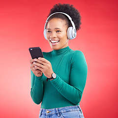 Image showing Happy woman, phone and listening to music on headphones against a red studio background. African female person smile with headset in audio streaming, entertainment or sound track on mobile smartphone