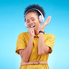 Image showing Happy woman, headphones and singing while listening to music for karaoke against a blue studio background. Female person enjoying audio sound track or song with headset for entertainment on mockup