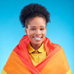 Image showing Pride, flag and portrait of black woman in studio for gay, rights and lgbtq lifestyle on blue background. Rainbow, freedom and face of lesbian African female happy, smile and confident with sexuality