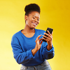 Image showing Happy black woman, phone and social media for networking or communication against a yellow studio background. African female person smile for online browsing or chatting on mobile smartphone app