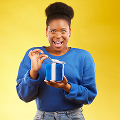 Image showing Gift, present and portrait of black woman with a surprise happy isolated in a yellow studio background for a birthday. Shocked, box and excited person to celebrate, party and holiday as a winner