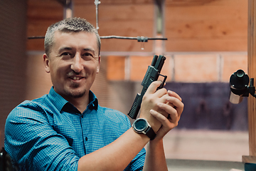 Image showing A man practices shooting a pistol in a shooting range while wearing protective headphones