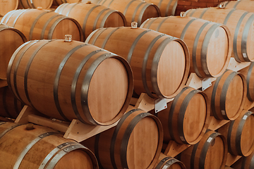 Image showing Wine or cognac barrels in the cellar of the winery, Wooden wine barrels in perspective. Wine vaults.Vintage oak barrels of craft beer or brandy.