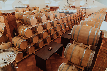 Image showing Wine or cognac barrels in the cellar of the winery, Wooden wine barrels in perspective. Wine vaults.Vintage oak barrels of craft beer or brandy.