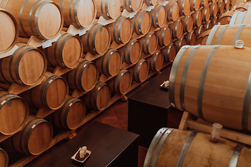 Image showing Wine or cognac barrels in the cellar of the winery, Wooden wine barrels in perspective. Wine vaults.Vintage oak barrels of craft beer or brandy.