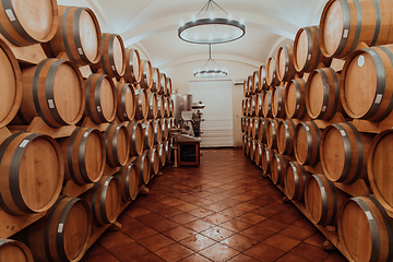 Image showing Wine or cognac barrels in the cellar of the winery, Wooden wine barrels in perspective. Wine vaults.Vintage oak barrels of craft beer or brandy.