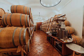 Image showing Wine or cognac barrels in the cellar of the winery, Wooden wine barrels in perspective. Wine vaults.Vintage oak barrels of craft beer or brandy.