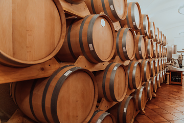 Image showing Wine or cognac barrels in the cellar of the winery, Wooden wine barrels in perspective. Wine vaults.Vintage oak barrels of craft beer or brandy.