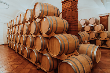 Image showing Wine or cognac barrels in the cellar of the winery, Wooden wine barrels in perspective. Wine vaults.Vintage oak barrels of craft beer or brandy.