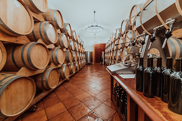 Image showing Wine or cognac barrels in the cellar of the winery, Wooden wine barrels in perspective. Wine vaults.Vintage oak barrels of craft beer or brandy.