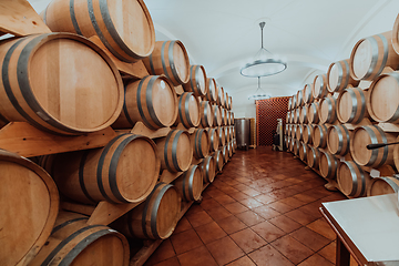 Image showing Wine or cognac barrels in the cellar of the winery, Wooden wine barrels in perspective. Wine vaults.Vintage oak barrels of craft beer or brandy.