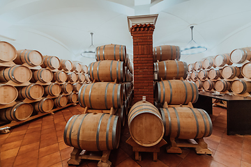 Image showing Wine or cognac barrels in the cellar of the winery, Wooden wine barrels in perspective. Wine vaults.Vintage oak barrels of craft beer or brandy.