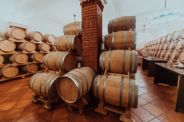 Image showing Wine or cognac barrels in the cellar of the winery, Wooden wine barrels in perspective. Wine vaults.Vintage oak barrels of craft beer or brandy.