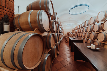 Image showing Wine or cognac barrels in the cellar of the winery, Wooden wine barrels in perspective. Wine vaults.Vintage oak barrels of craft beer or brandy.