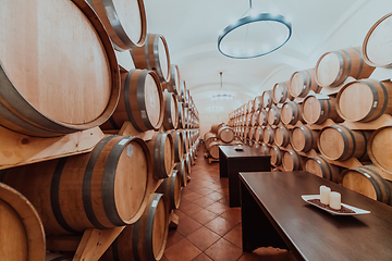 Image showing Wine or cognac barrels in the cellar of the winery, Wooden wine barrels in perspective. Wine vaults.Vintage oak barrels of craft beer or brandy.