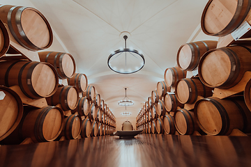 Image showing Wine or cognac barrels in the cellar of the winery, Wooden wine barrels in perspective. Wine vaults.Vintage oak barrels of craft beer or brandy.