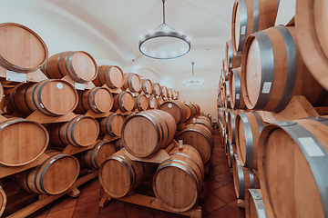 Image showing Wine or cognac barrels in the cellar of the winery, Wooden wine barrels in perspective. Wine vaults.Vintage oak barrels of craft beer or brandy.