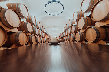 Image showing Wine or cognac barrels in the cellar of the winery, Wooden wine barrels in perspective. Wine vaults.Vintage oak barrels of craft beer or brandy.