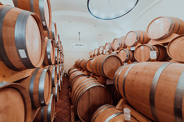 Image showing Wine or cognac barrels in the cellar of the winery, Wooden wine barrels in perspective. Wine vaults.Vintage oak barrels of craft beer or brandy.