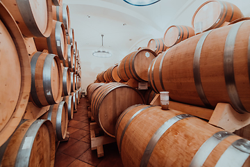 Image showing Wine or cognac barrels in the cellar of the winery, Wooden wine barrels in perspective. Wine vaults.Vintage oak barrels of craft beer or brandy.