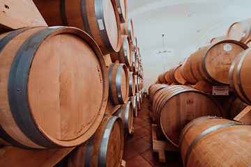 Image showing Wine or cognac barrels in the cellar of the winery, Wooden wine barrels in perspective. Wine vaults.Vintage oak barrels of craft beer or brandy.