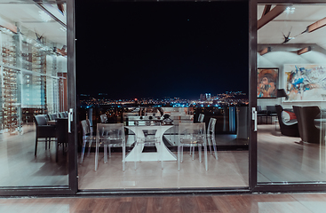 Image showing A beautiful house with a beautiful view of the night city. Luxury living room and tereasa with a view of the city. Night photo of a luxury house