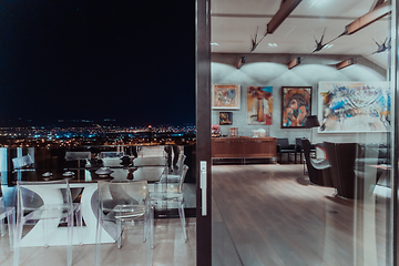 Image showing A beautiful house with a beautiful view of the night city. Luxury living room and tereasa with a view of the city. Night photo of a luxury house