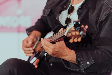 Image showing Practicing in playing guitar. Handsome young men playing guitar