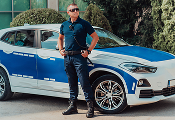 Image showing A policeofficer patrols the city. A police officer with sunglasses patroling in the city with an official police car