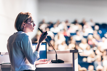 Image showing Female speaker giving a talk on corporate business conference. Unrecognizable people in audience at conference hall. Business and Entrepreneurship event.