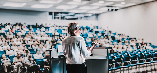 Image showing Female speaker giving a talk on corporate business conference. Unrecognizable people in audience at conference hall. Business and Entrepreneurship event.