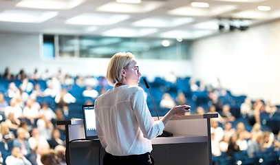 Image showing Female speaker giving a talk on corporate business conference. Unrecognizable people in audience at conference hall. Business and Entrepreneurship event.