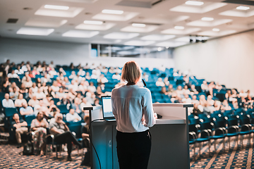 Image showing Female speaker giving a talk on corporate business conference. Unrecognizable people in audience at conference hall. Business and Entrepreneurship event.