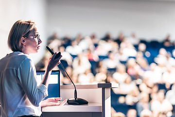 Image showing Female speaker giving a talk on corporate business conference. Unrecognizable people in audience at conference hall. Business and Entrepreneurship event.