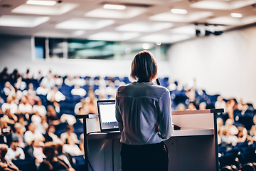 Image showing Female speaker giving a talk on corporate business conference. Unrecognizable people in audience at conference hall. Business and Entrepreneurship event.