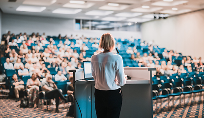 Image showing Female speaker giving a talk on corporate business conference. Unrecognizable people in audience at conference hall. Business and Entrepreneurship event.