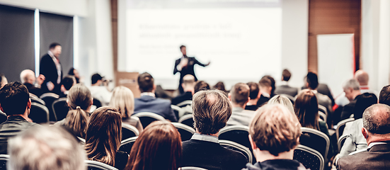 Image showing Speaker giving a talk in conference hall at business event. Rear view of unrecognizable people in audience at the conference hall. Business and entrepreneurship concept.