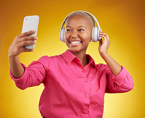 Image showing Smile, selfie and black woman with headphones for music, radio and podcast in studio isolated on a yellow background. Profile picture, photographer and African person or influencer on social media