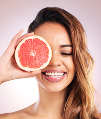 Image showing Citrus, grapefruit and face of woman with healthy, natural or organic beauty isolated in a brown studio background. Excited, eyes and young female person with vitamin c for skincare or detox