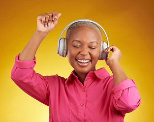 Image showing Music headphones, smile and black woman dancing in studio isolated on a yellow background. African person, happy and listening to radio, jazz or streaming audio, podcast and hearing sound with energy