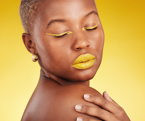 Image showing Creative, makeup and woman in a studio with cosmetic eyeliner and lipstick for cosmetology. Self care, glamour and young African female model with a colorful face routine by a yellow background.