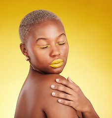 Image showing Beauty, cosmetic and young woman in a studio with eyeliner and lipstick for cosmetology. Self care, makeup and creative African female model with a colorful glamour face routine by yellow background.