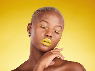 Image showing Face, makeup and lipstick with a black woman in studio on a yellow background for creative, beauty or cosmetics. Gold, color and eyeshadow on young model with eyes closed for fashion or aesthetic