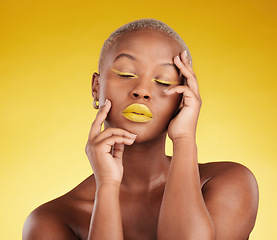 Image showing Creative, makeup and face with lipstick or black woman in studio on a yellow background for art, beauty or cosmetics. Gold, color and eyeshadow on calm model with eyes closed for fashion or aesthetic