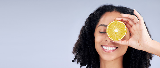 Image showing Skincare, wellness and woman with lemon eye or fruit for nutrition in grey studio background or banner. Dermatology, hand and smile with girl or vitamin c for natural facial or diet in mockup space.