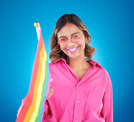 Image showing Woman, lgbtq and rainbow flag in studio portrait, sunglasses and icon for pride with human rights by blue background. Gen z girl, lesbian student and wave sign for solidarity, freedom and inclusion