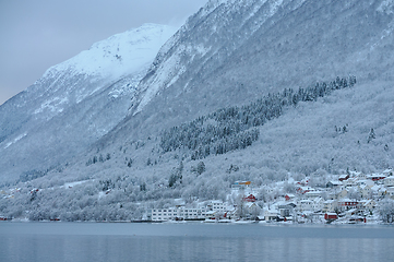 Image showing cluster of houses by the sea under snow-covered high mountains