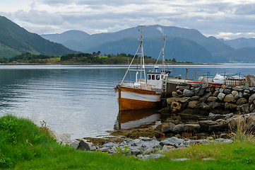 Image showing small fishing boat by a stone breakwater